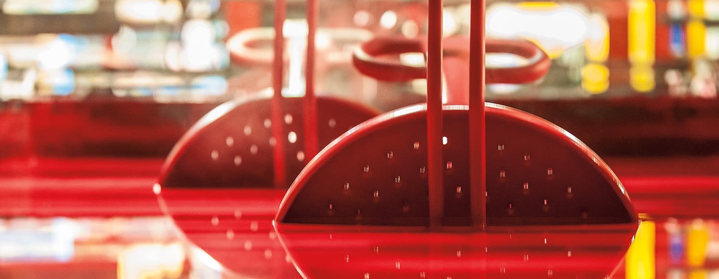 Spinning playground equipment being dipped into a vat of red TenderTuff rubber coating.