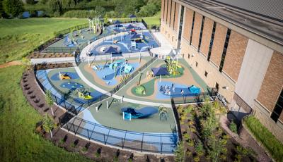 Elevated view of a large half moon shaped play area divided by fencing for specific play areas based on age designed with a religious theme of the creation of the world.