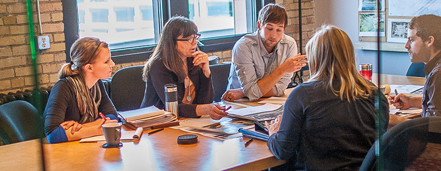 A group gathered around a wood conference table for a playground planning business meeting.