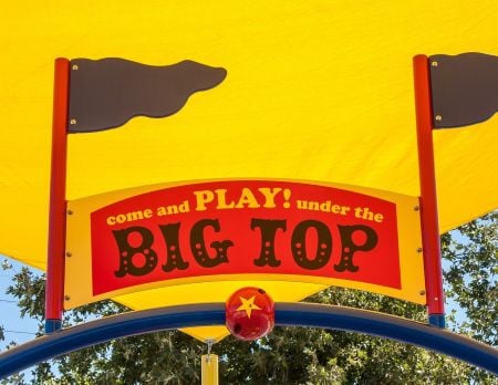 Custom playground sign that reads "come and PLAY! under the BIG TOP" and is designed to look like the sign over a circus tent.