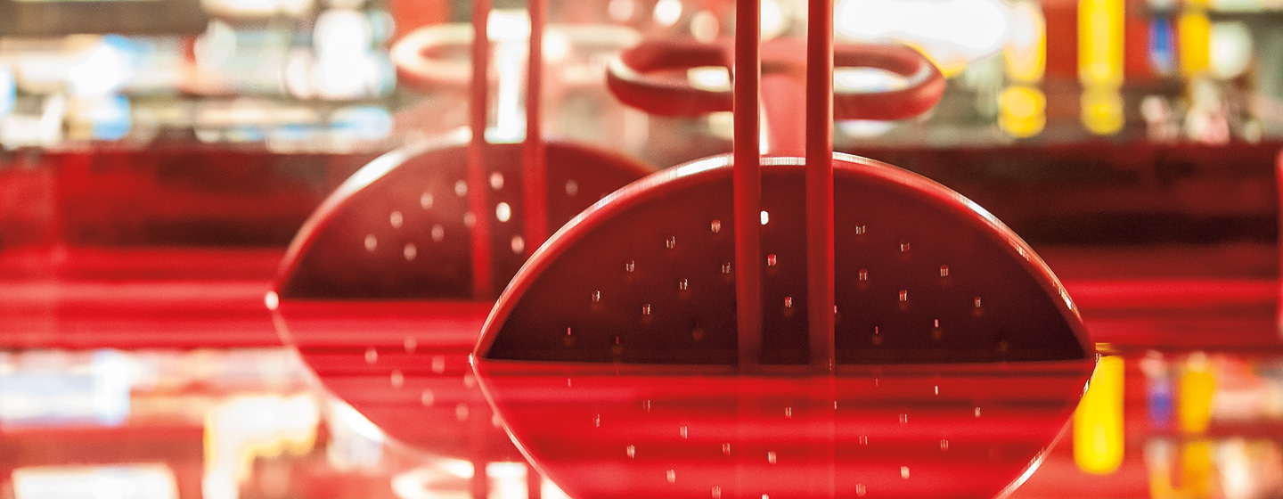 Spinning playground equipment being dipped into a vat of red Tender Tuff rubber coating.