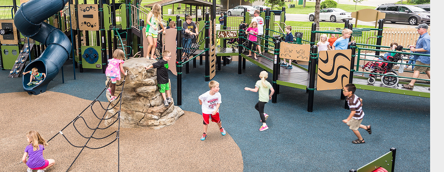 Children run and play around inclusive playground.