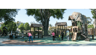 Parents play with their kids at this naturally-themed playground