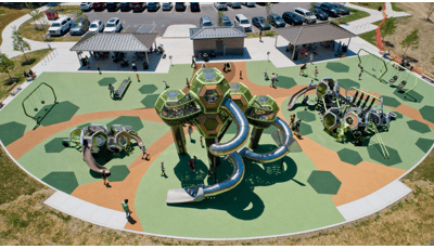 Elevated view of a park playground with play structures made of hexagonal connecting pods and other surrounding play activities.