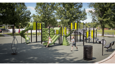 Boy and girl play together at Saratoga Park. The girl rides down slide while boy runs along play structure, as adults watch in the background.