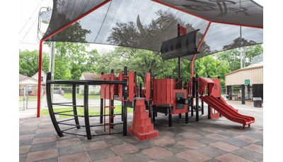 Custom pirate ship designed playground sitting under black skull with cross swords shade canopy.