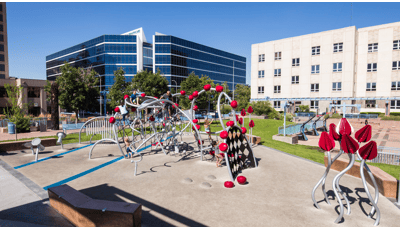 Children playing on an artistic, sculptural playground made to look like a Prickly Pear Cactus with bright red fruit